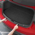 ACP11540 - Tesla Series Trunk Sill Guard Two hands pressing the Spigen bumper protector trim into both edges of an open Tesla trunk