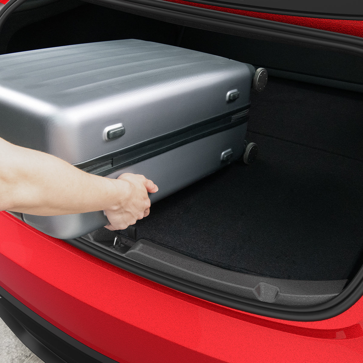 ACP11540 - Tesla Series Trunk Sill Guard Hand loading a silver suitcase into a Tesla trunk protected by the black Spigen bumper scuff plate