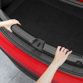 ACP11540 - Tesla Series Trunk Sill Guard Hands pressing the Spigen bumper protector into place along the edge of a Tesla trunk opening