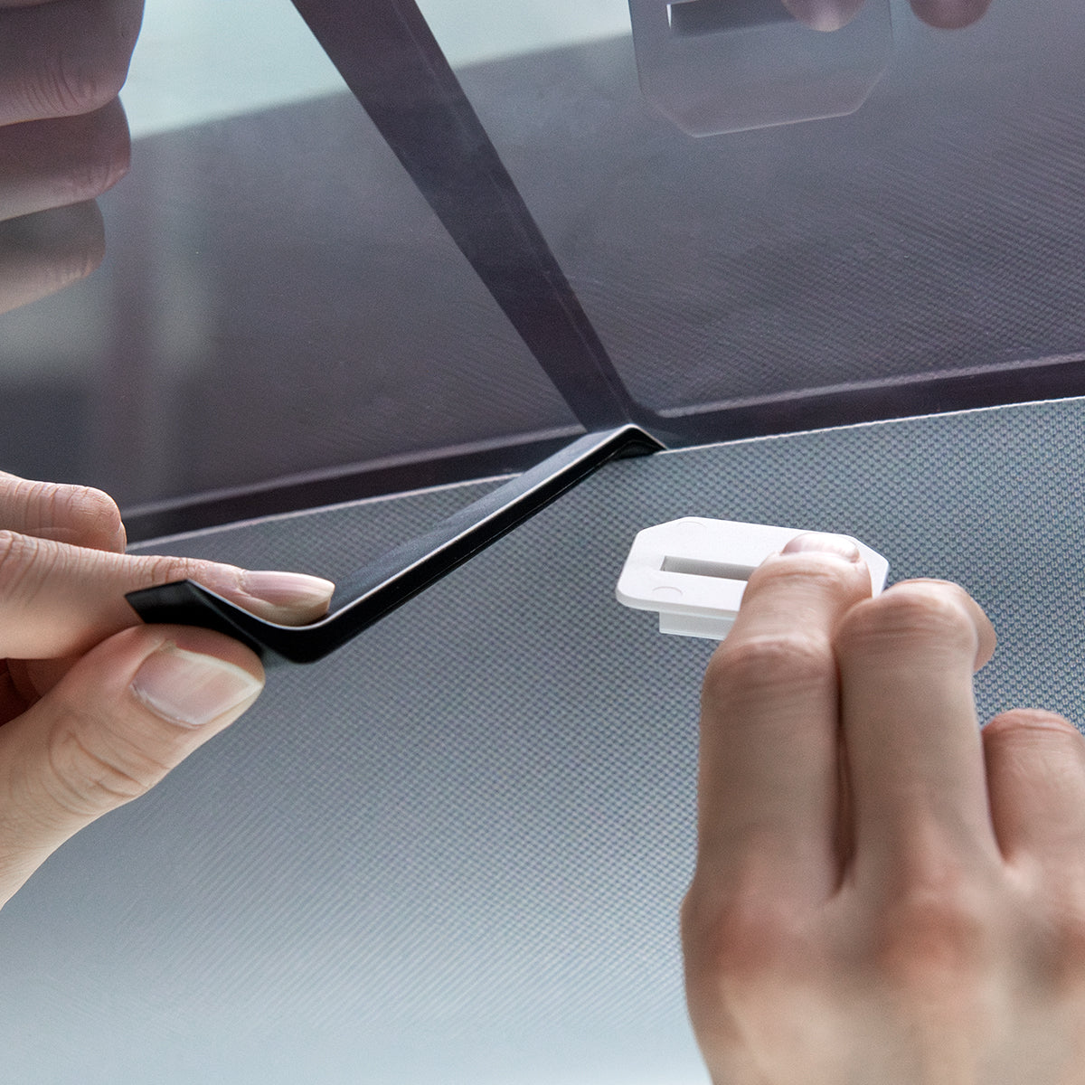 ACP09568 - Model Y (2025) CryoShade Sunroof in Gray showing a person holding a prying tool on other hand and clip on the other