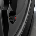 ACP11371 - Universal Tire Valve Stem Cap | VS100TS/R in Red showing a side view of the matte black hexagonal cap with red Tesla logo installed on a vehicle wheel valve stem.